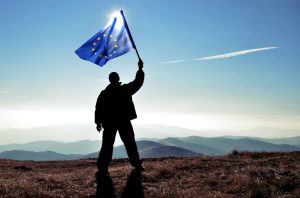 successfull silhouette man winner waving Europian Union flag on top of the mountain peak